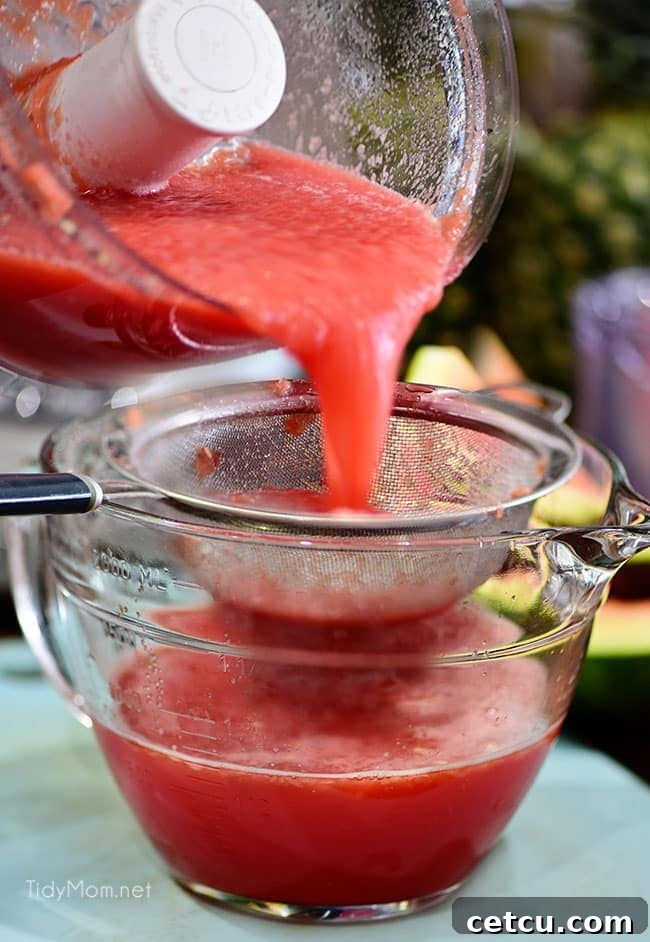 Close-up of watermelon purée being strained through a fine-mesh sieve to remove pulp and seeds, ensuring a smooth wine slushie.