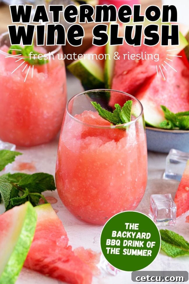Two stemless wine glasses filled with red watermelon wine slushies, garnished with fresh mint, sitting on a light wooden table in an outdoor setting. Highlights the refreshing nature and elegant presentation.