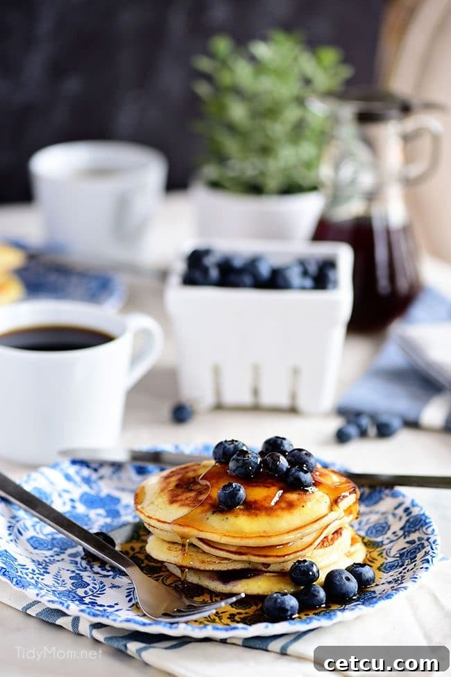 A beautifully set table featuring a bountiful platter of The Best Homemade Blueberry Pancakes, garnished with fresh berries and a pitcher of maple syrup, inviting diners to indulge.