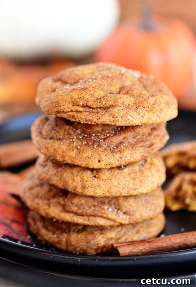 A stack of soft and fluffy Pumpkin Snickerdoodle cookies on a plate, showcasing their inviting golden-orange hue and sugar-spice coating.