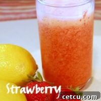 Close-up of a frosty glass of frozen strawberry lemonade with condensation, garnished with a fresh strawberry