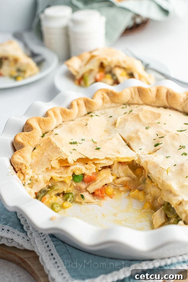 A freshly baked chicken pot pie in a pie dish, with two generous servings already removed, revealing the delicious, creamy interior.