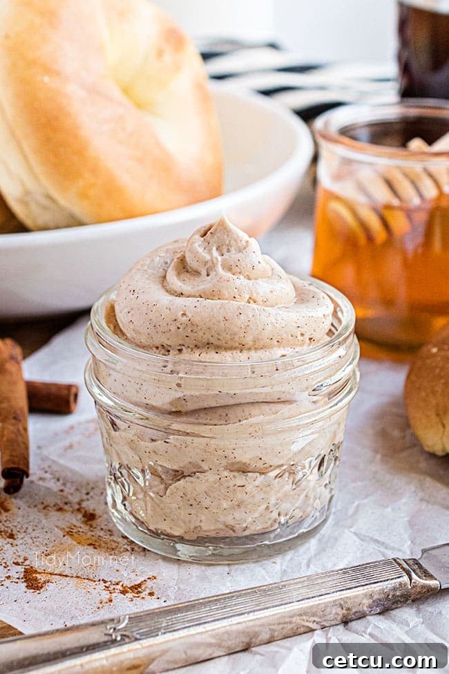 A small jar filled with perfectly whipped cinnamon honey butter on a rustic wooden surface.