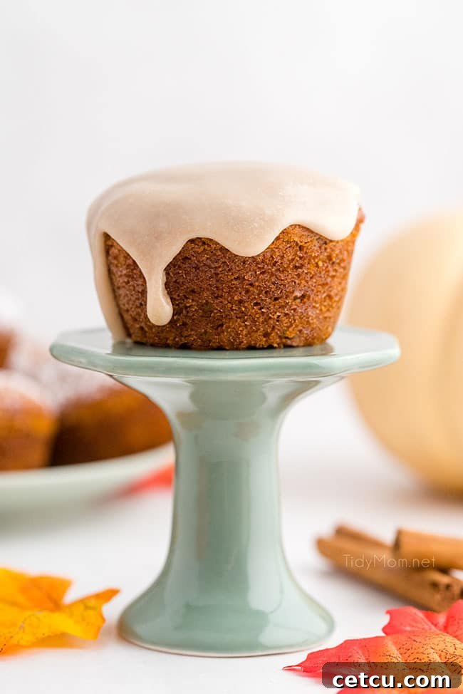 maple glazed pumpkin muffins on a teal cupcake stand, showcasing their golden-brown tops and sweet drizzle
