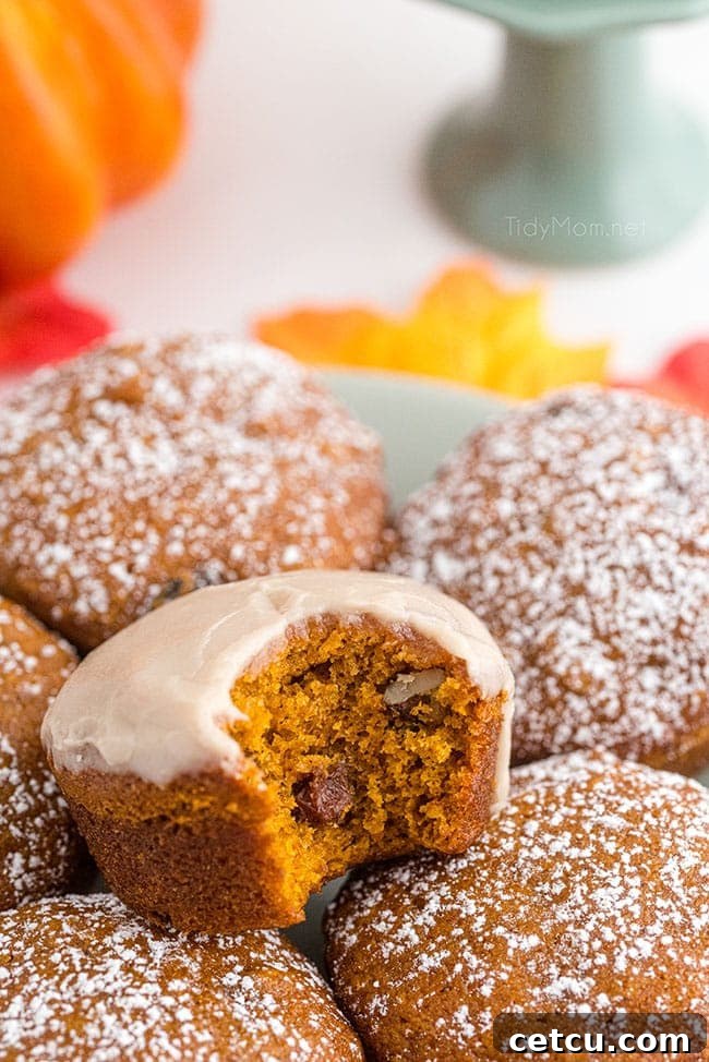 a maple glazed pumpkin muffin with a bite taken out, showing its moist, tender interior