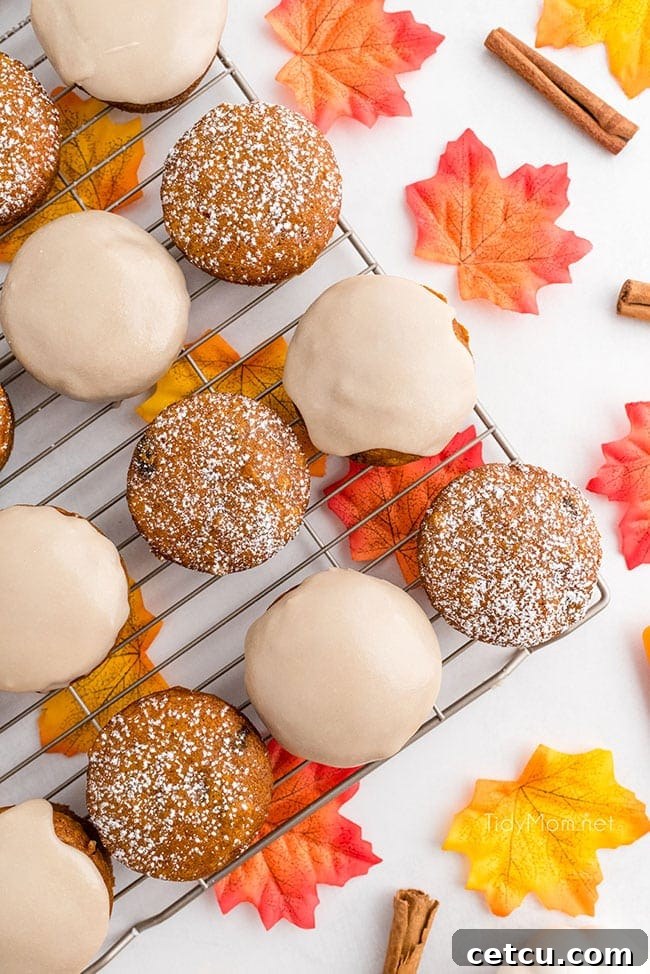 glazed and powdered sugar topped pumpkin muffins cooling on a wire rack, ready to be enjoyed