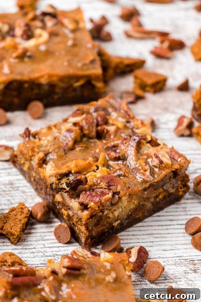 Autumn's Magical Seven Layer Pumpkin Bars 6 pumpkin 7-layer bars on a counter with scattered cinnamon chips, highlighting the delicious topping