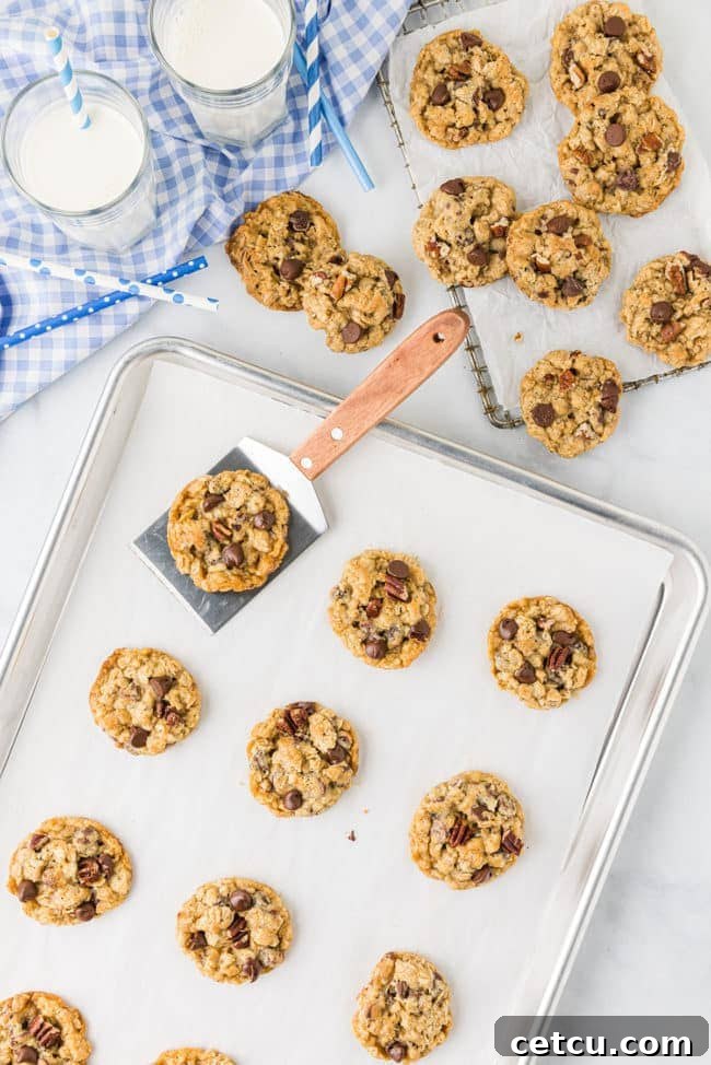 A baking sheet filled with freshly baked Ranger Cookies, cooling straight out of the oven, their golden edges visible.