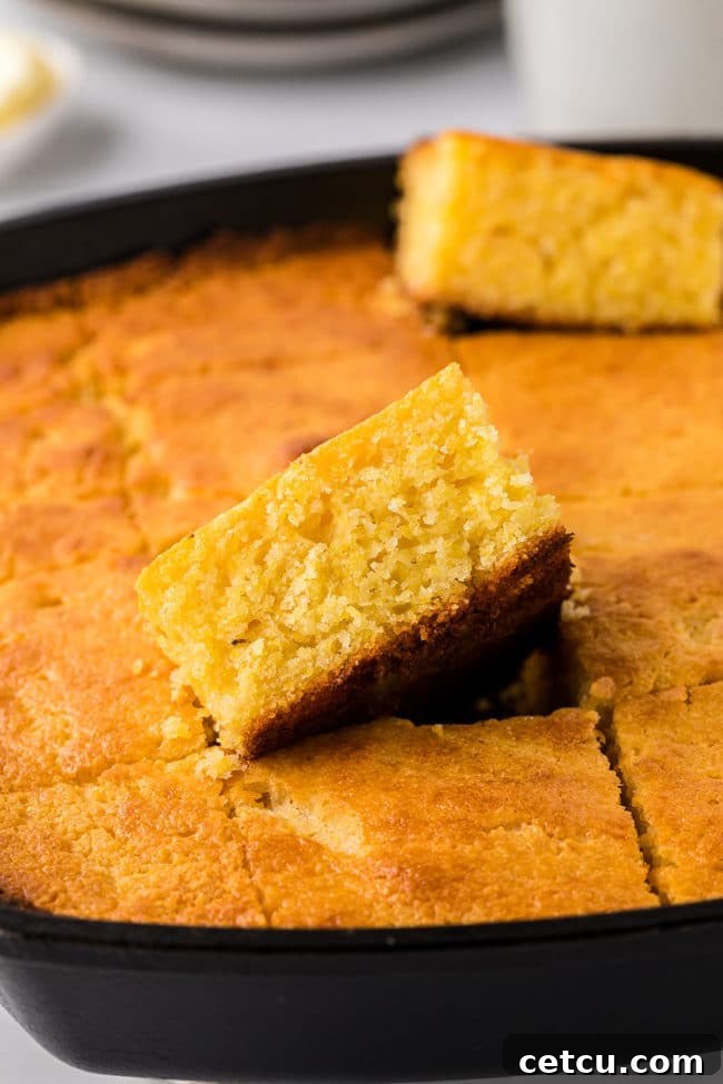 Golden-brown cornbread, perfectly baked and sliced, sitting beautifully in a cast iron skillet.