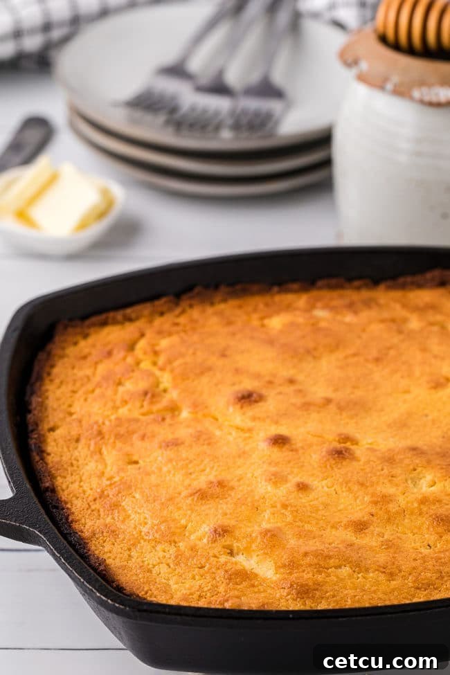 A glorious golden cornbread, hot out of the oven, nestled in a seasoned cast iron skillet.