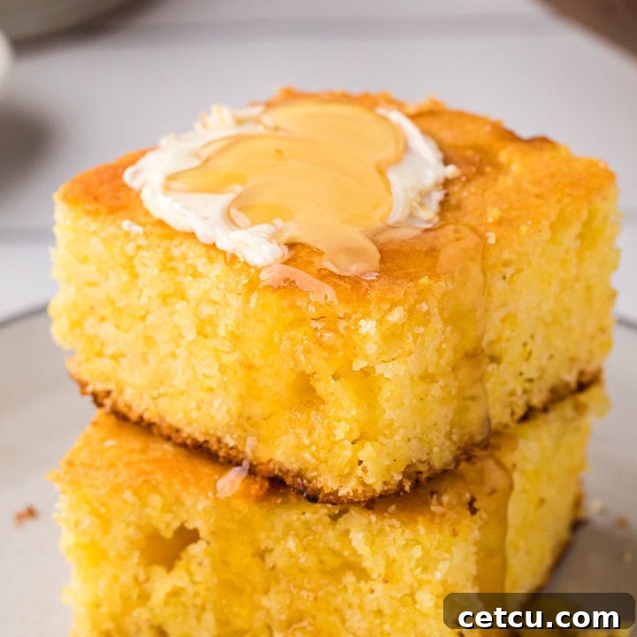 Two servings of cornbread stacked and topped with butter and honey, demonstrating the moist and fluffy texture.