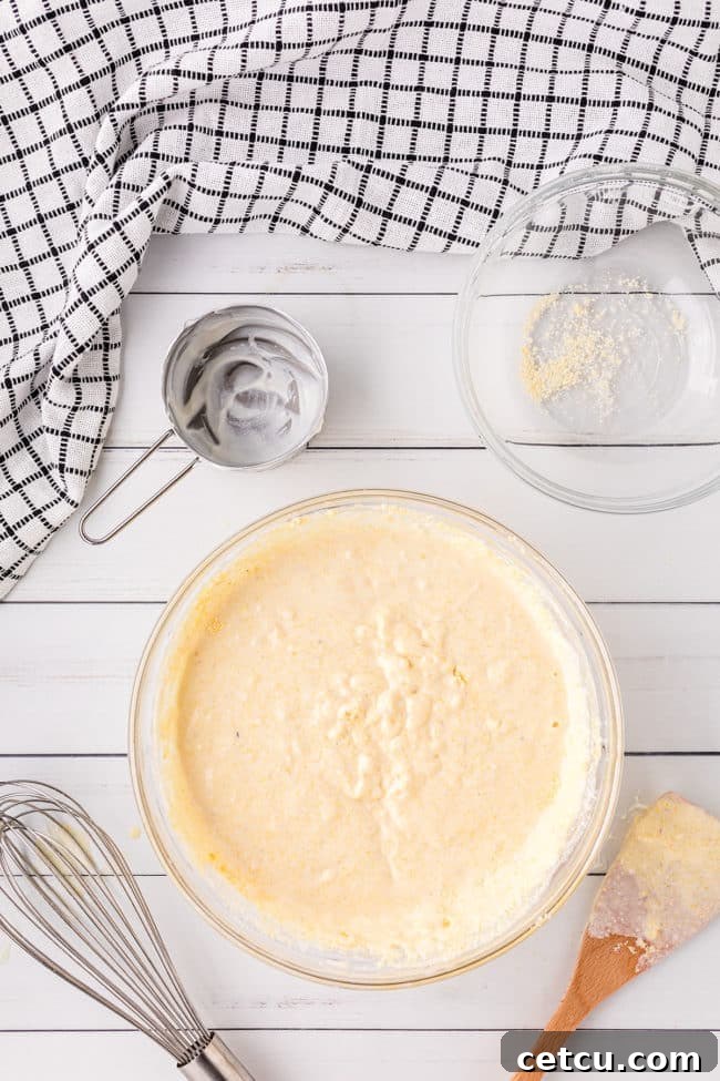 Step 3: Gently stirring Jiffy cornbread mix into the wet ingredients.