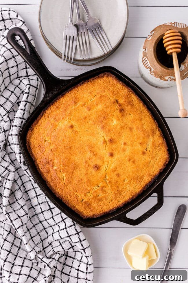 A freshly baked, golden brown cornbread in a cast iron skillet, ready to be served.