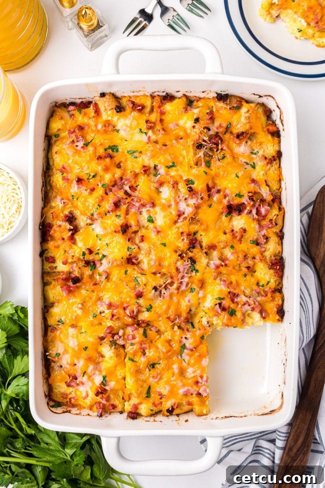 A whole English muffin breakfast casserole in a baking dish, with one serving already removed, ready for more.