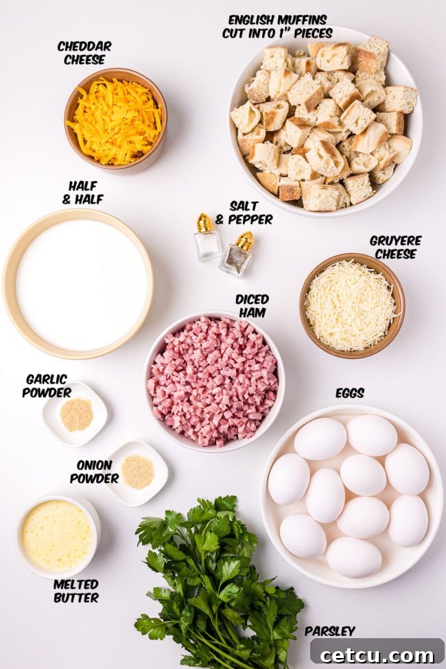 Assortment of fresh ingredients for an English Muffin Breakfast Casserole laid out on a kitchen counter, including English muffins, ham, various cheeses, eggs, and seasonings.