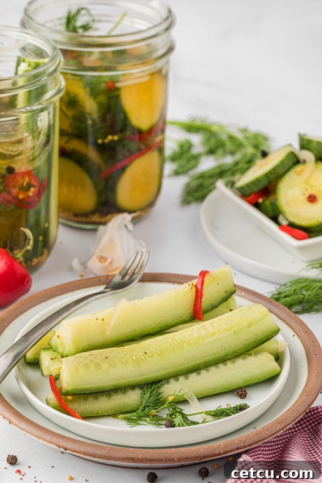 A tempting plate of crisp pickle spears, with jars of homemade refrigerator pickles providing a delicious backdrop, ready for any meal.