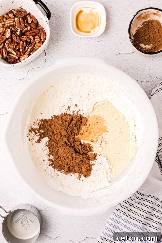 Step 10: Adding evaporated milk, cocoa powder, and vanilla extract to the frosting mixture.