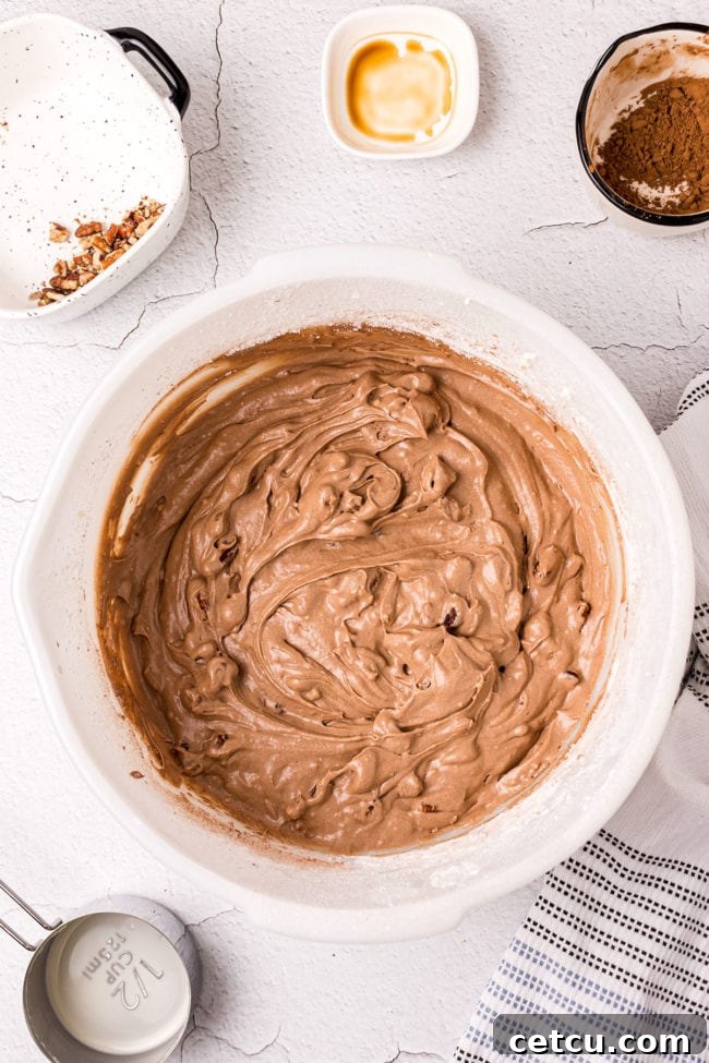 Step 12: Folding in chopped pecans into the finished chocolate frosting mixture.