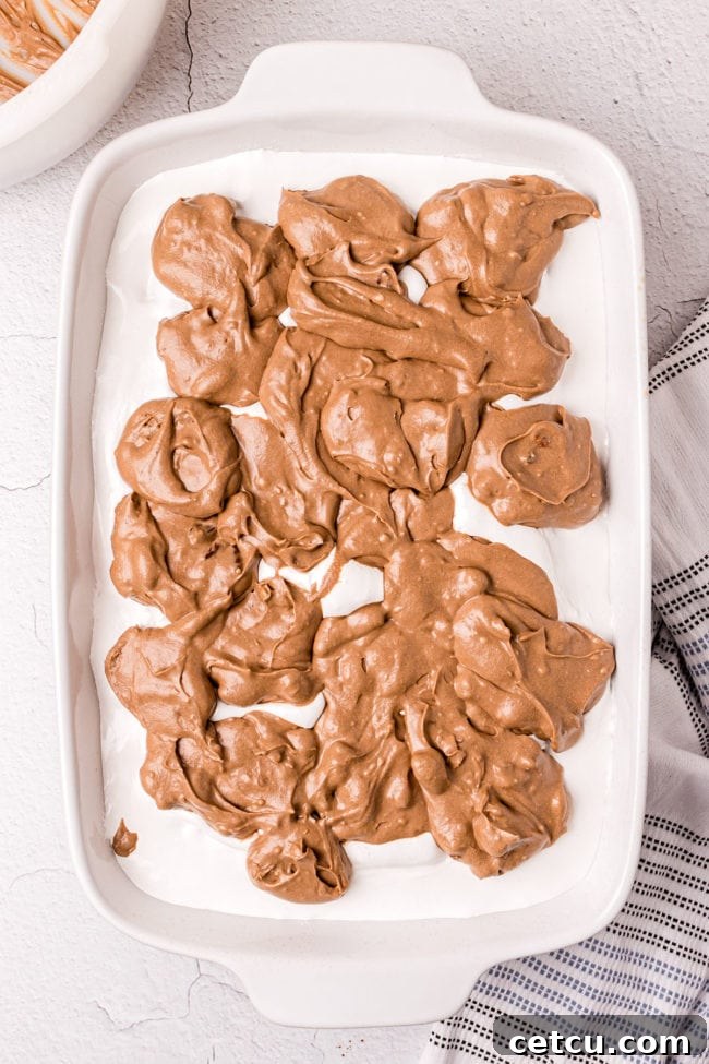 Step 13: Spreading the rich chocolate frosting over the marshmallow layer of the cooled Mississippi Mud Cake.