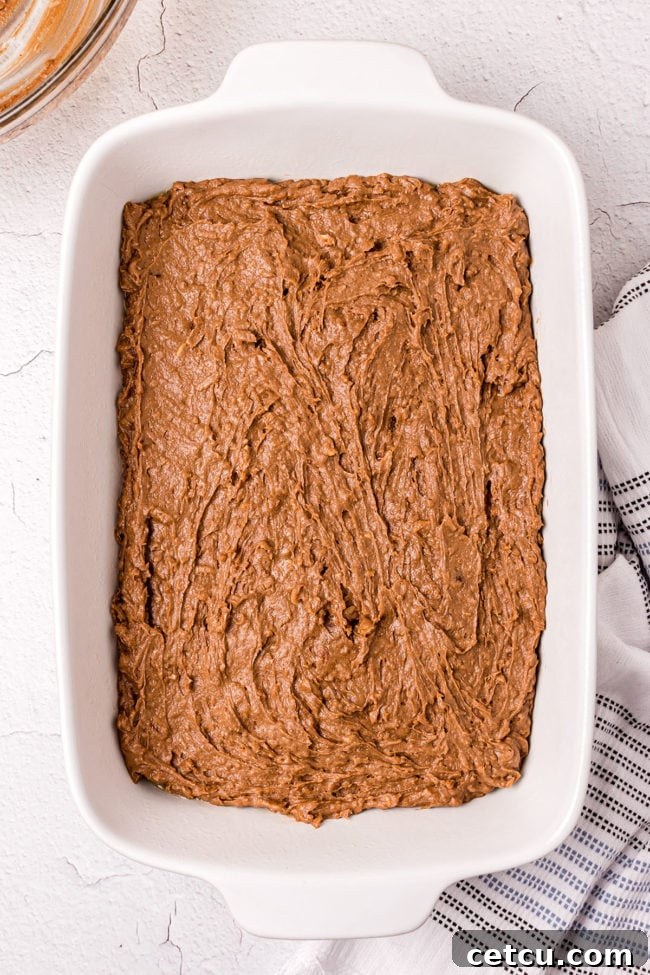 Step 6: Spreading a layer of gooey marshmallow creme over the warm, freshly baked chocolate mud cake.