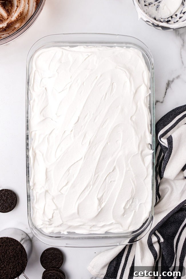 Step 8: Sprinkling reserved Oreo crumbs as the final garnish for the No-Bake Oreo Delight.