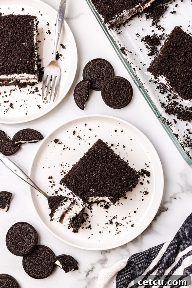 An overhead shot of a freshly made No-Bake Oreo Delight on a plate, garnished with whole Oreo cookies and a fork, ready to be enjoyed.