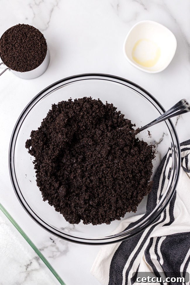 Step 3: Pressing the Oreo crust mixture firmly into a 9x13 inch baking dish.