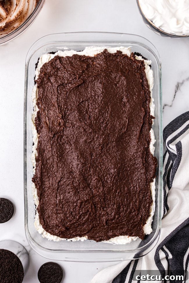 Step 6: Spreading the thickened chocolate pudding evenly over the cream cheese layer.