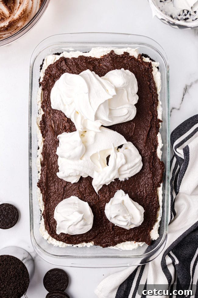 Step 7: Adding the final layer of Cool Whip on top of the chocolate pudding.