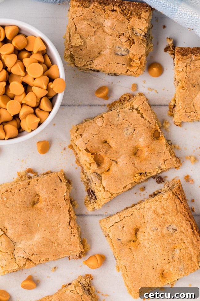Butterscotch blondies, freshly cut into squares, beautifully arranged on a countertop with a bowl of butterscotch chips nearby, inviting you to grab one.