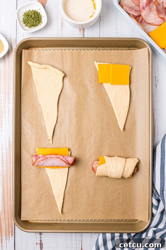 Step 3: Placing ham and cheese on the wide end of a crescent roll triangle before rolling.