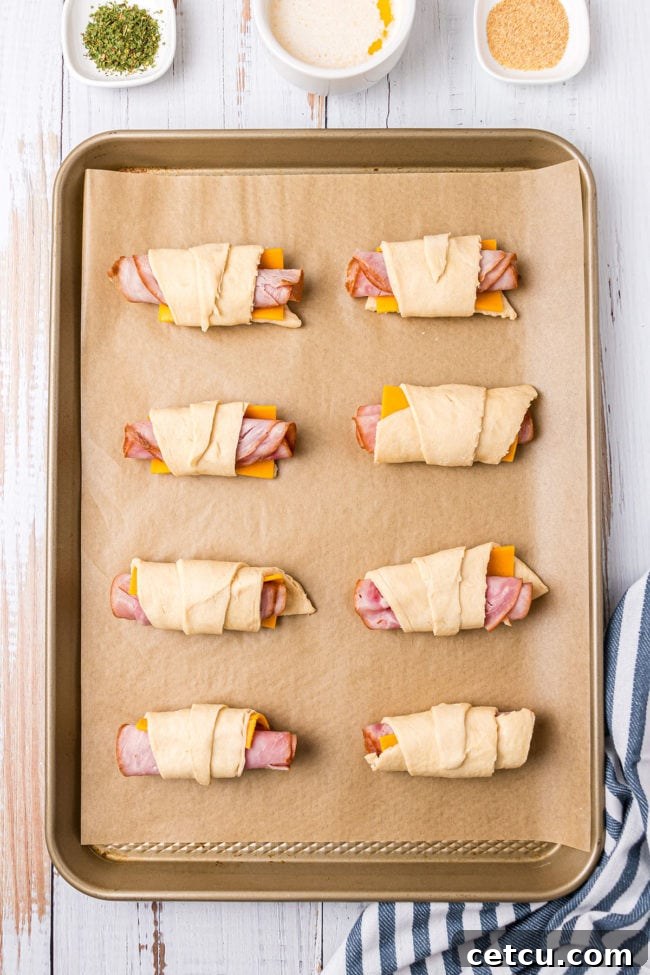 Step 4: Rolled crescent sandwiches placed neatly on a parchment-lined baking sheet.