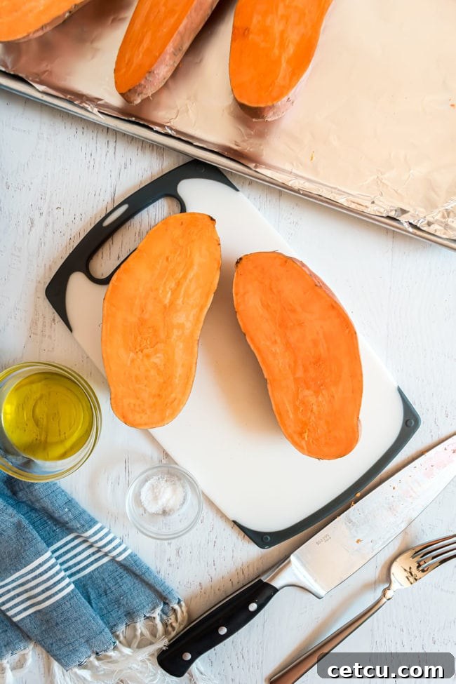 raw sweet potato cut in half lengthwise on a cutting board
