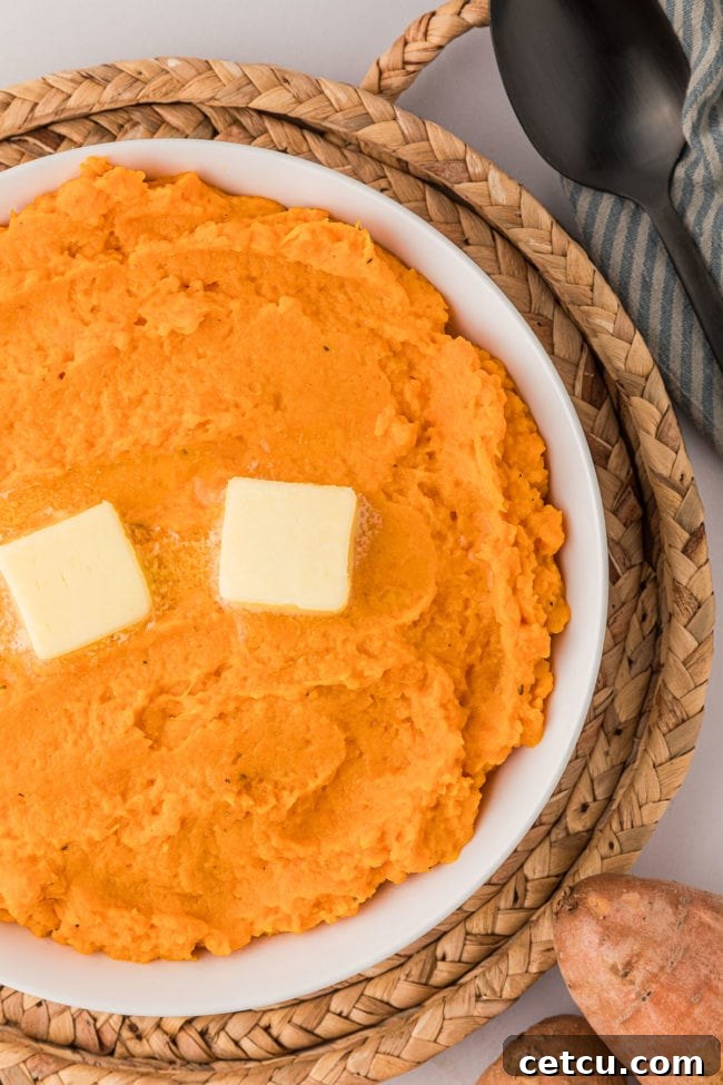 mashed sweet potatoes in a bowl with 2 pats of butter on top