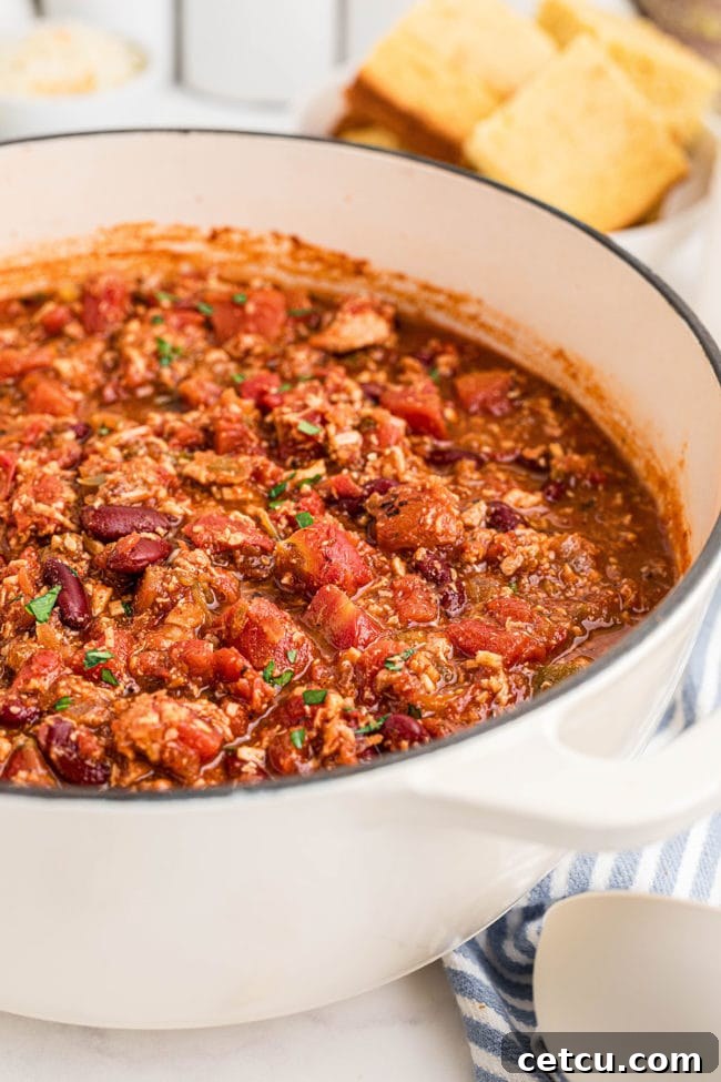 A white Dutch oven brimming with perfectly cooked turkey chili, ready to be served.