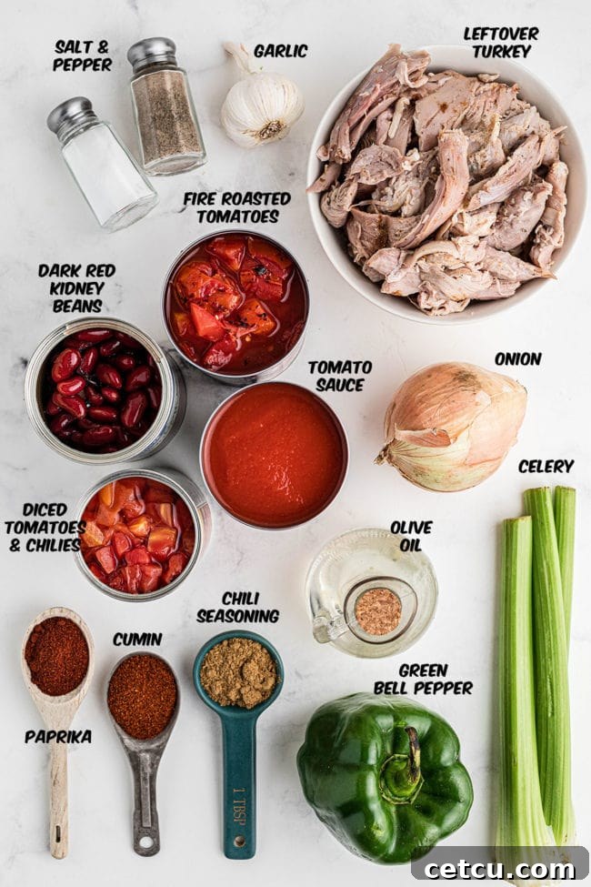 Ingredients for homemade leftover turkey chili laid out on a kitchen counter, including canned tomatoes, beans, spices, vegetables, and shredded turkey.