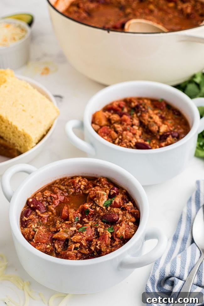 Two white soup bowls filled with homemade turkey chili, ready to be served and garnished.