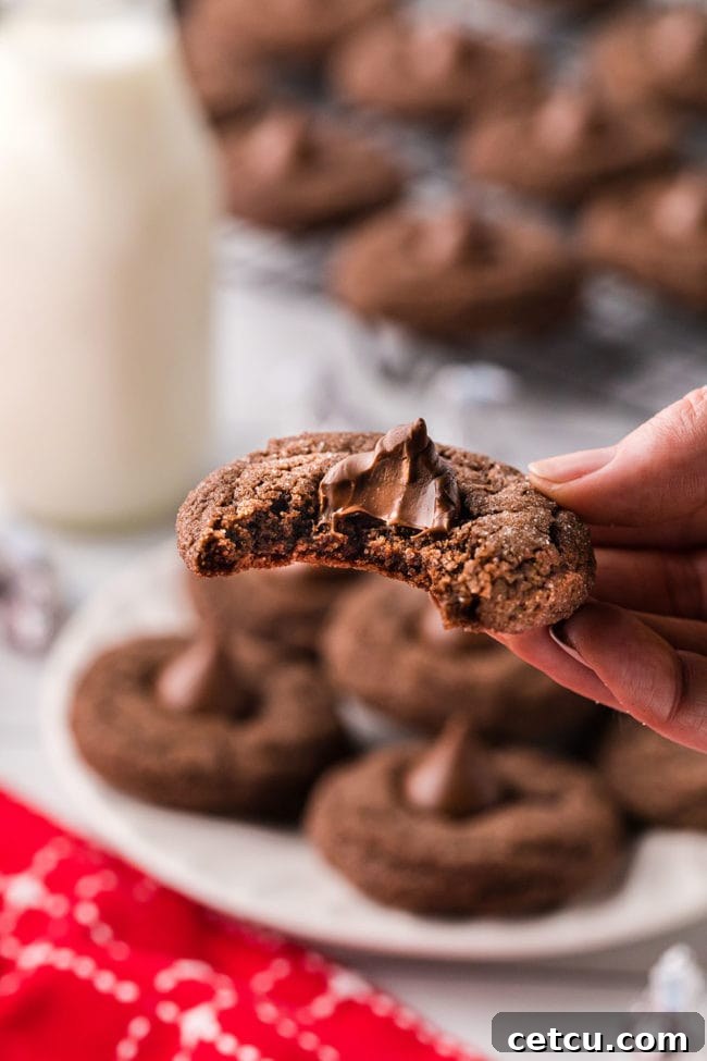 A close-up of a Double Chocolate Kiss Cookie with a bite taken out, revealing its soft, fudgy interior and the perfectly melted Hershey's Kiss.