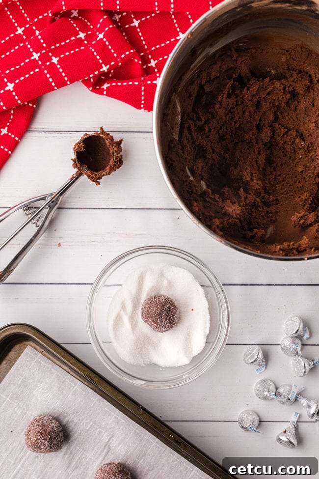 A close-up shot of a hand rolling chocolate cookie dough into perfect balls with the help of a cookie scoop.