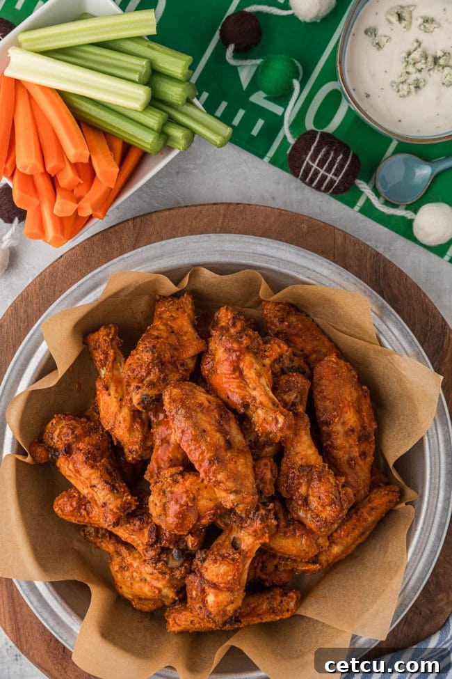 Crispy oven baked chicken wings served in a large bowl with fresh carrots and celery sticks, perfect for a game day party spread.