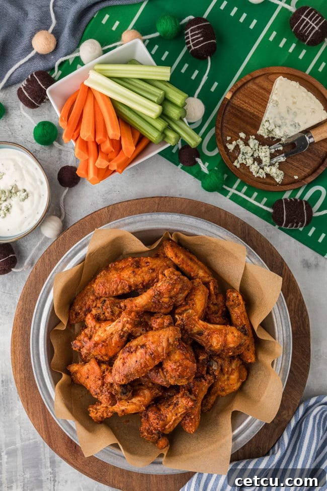 A bowl of crispy oven-baked chicken wings ready for a game day party, surrounded by football-themed decorations.