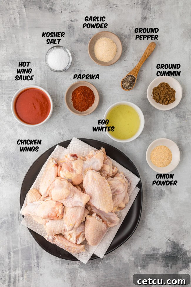 A collection of fresh ingredients laid out for oven baked crispy wings, including raw chicken wings, eggs, and various spices.