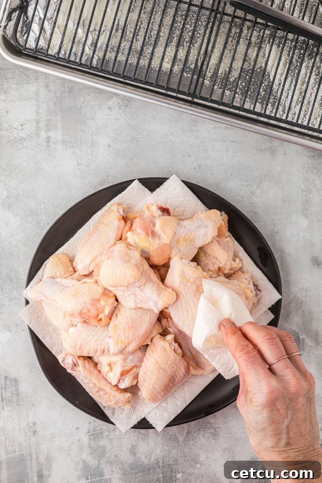 Raw, uncooked chicken wings neatly arranged on a tray, ready for seasoning and preparation.