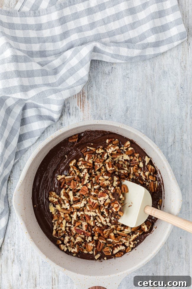 Step 3: Stirring in chopped pecans into the melted fudge mixture