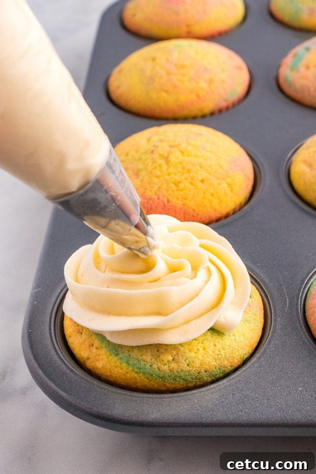 A hand expertly piping a swirl of buttercream frosting onto a freshly baked Spring cupcake, creating an elegant decoration.