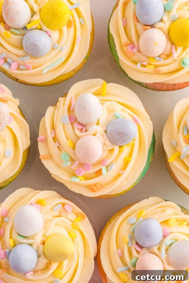 A close-up of a decorated Easter cupcake with a generous swirl of buttercream, pastel sprinkles, and mini chocolate eggs.