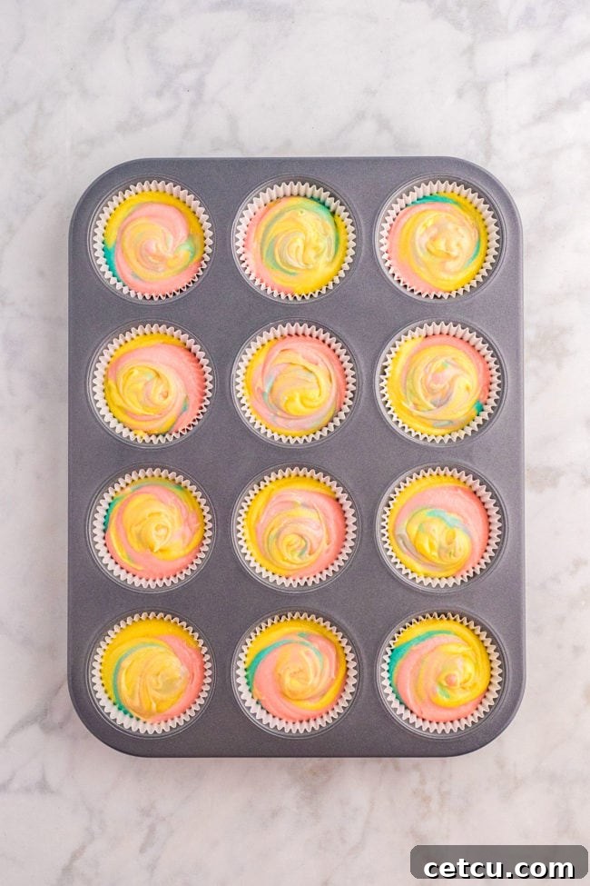 Another view of cupcake batter with three pastel colors expertly swirled to create a beautiful marble pattern before baking.