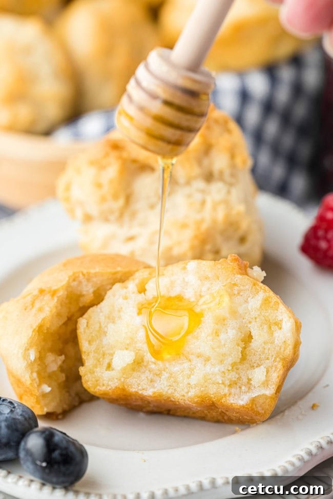 A close-up of a warm mayonnaise biscuit, gently drizzled with golden honey, emphasizing its soft texture and inviting appeal.