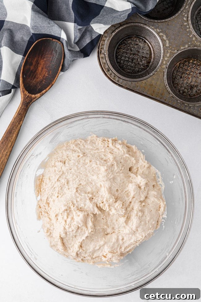 The mayonnaise biscuit dough, now fully combined, sits in a glass mixing bowl, exhibiting a loose, wet batter consistency, ready for the next step.