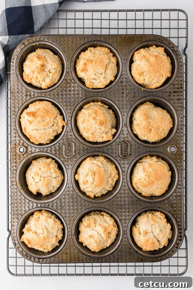 Freshly baked golden brown mayonnaise biscuits still in the muffin tin, perfectly puffed and ready to be removed.